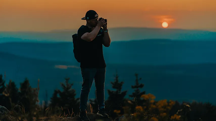 Person on top of a mountain at sunset.