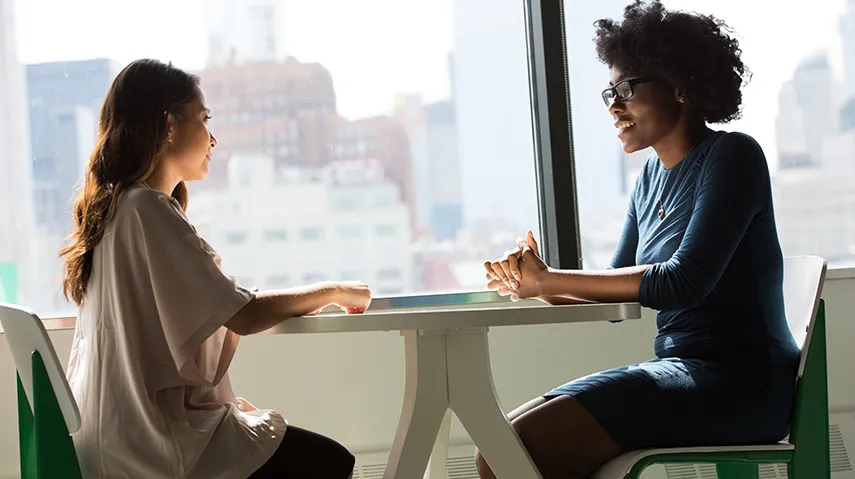 Student and staff member sitting at a table.