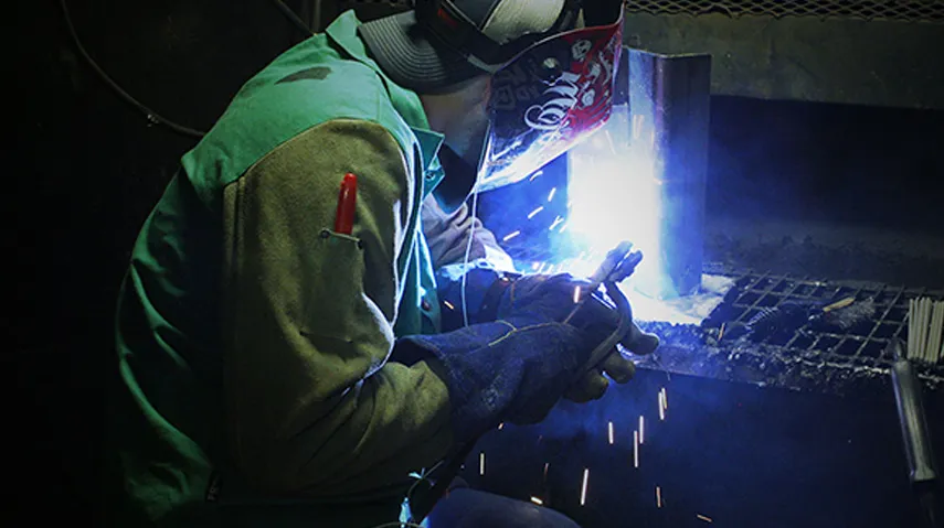 Masked welder making weld